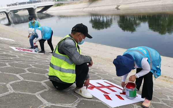 水务部门工作人员在河道护坡上涂刷警示语.jpg